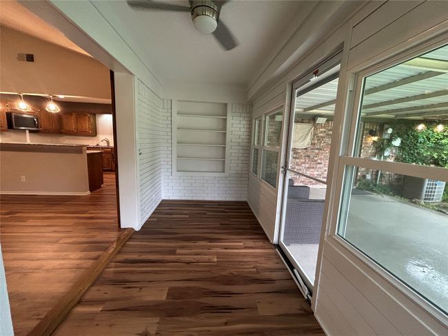 Unfurnished sunroom featuring ceiling fan, wood finished floors, and brick wall | Image 14