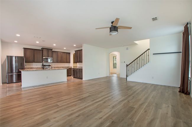 Unfurnished living room with arched walkways, ceiling fan, recessed lighting, light wood finished floors, and stairway | Image 9