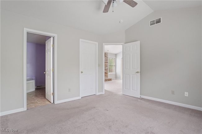 Unfurnished bedroom featuring carpet, vaulted ceiling, baseboards, ensuite bath, and a ceiling fan | Image 9
