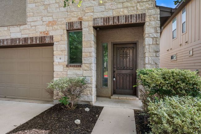 Doorway to property with stone siding and an attached garage | Image 37