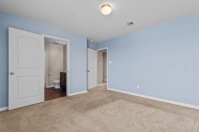 Unfurnished bedroom featuring baseboards, carpet, connected bathroom, and visible vents | Image 10