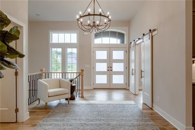 Entryway featuring a wealth of natural light, a chandelier, light wood-type flooring, and a barn door | Image 2