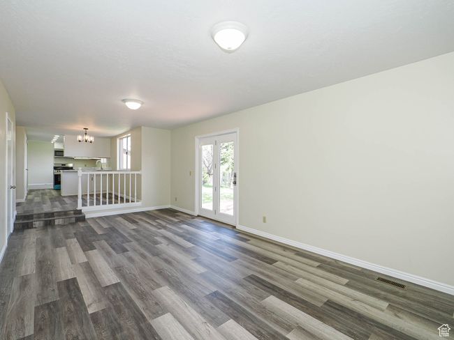 Empty room with dark wood-type flooring and a chandelier | Image 36