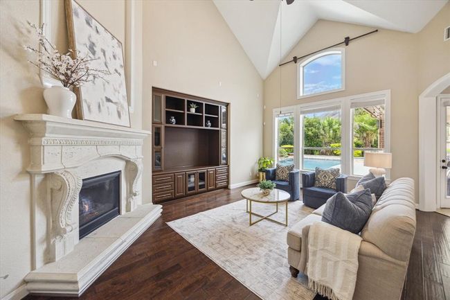 A grand stone gas log fireplace, custom built in entertainment center, soaring ceilings, and fabulous views of the backyard oasis encapsulate you when you enter this living space! | Image 9