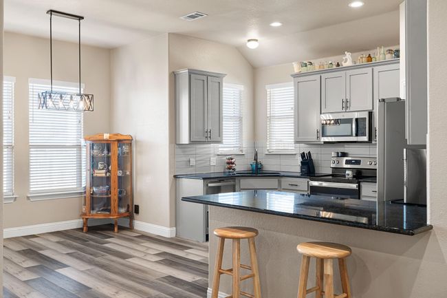 Kitchen featuring decorative backsplash, stainless steel appliances, a kitchen breakfast bar, light wood-type flooring, and a peninsula | Image 9