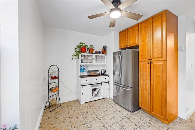 Kitchen with freestanding refrigerator, ceiling fan, baseboards, open shelves, and brown cabinets | Image 8