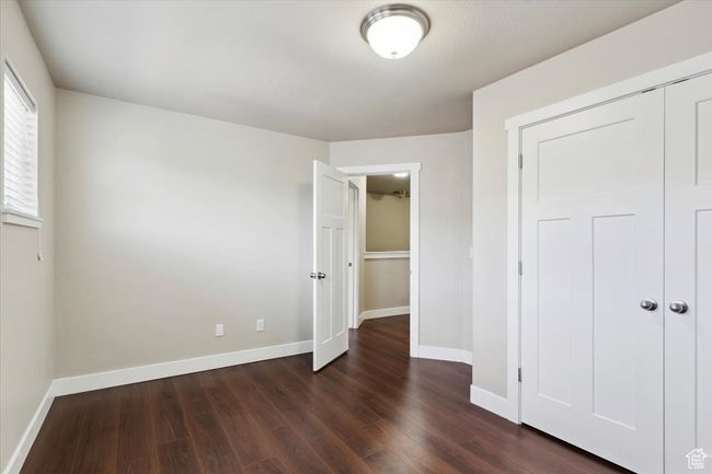 Unfurnished bedroom with dark wood finished floors, baseboards, and a closet | Image 23