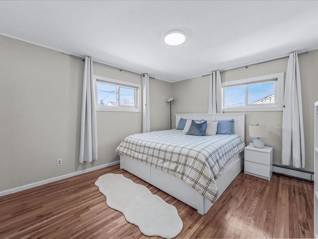 Bedroom with a baseboard radiator, wood finished floors, and baseboards | Image 15