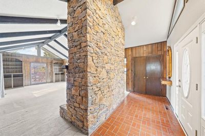 Tiled foyer opens into great room featuring beams, wooden walls, and high vaulted ceiling | Image 3