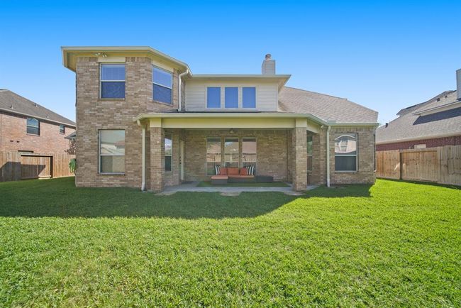 Perfect for outdoor relaxing, barbecuing and entertaining family and friends is the 21' x 8' covered patio with ceiling fan & lighting supported by decorative brick columns. Included in this full brick home is gated access to the front yard, spacious side yards, an automatic sprinkler system & french drains installed in 2022. The rain gutter system along the back of the home was added in 2021. | Image 47