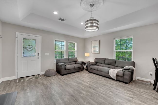 Living room featuring wood finished floors, a tray ceiling, an inviting chandelier, and a healthy amount of sunlight | Image 15
