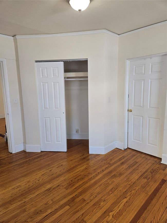 Unfurnished bedroom with ornamental molding, a closet, wood finished floors, and baseboards | Image 11