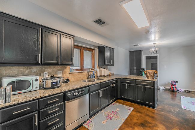 Unit 4904 Kitchen with tasteful backsplash, sink, stainless steel dishwasher, light stone counters, and kitchen peninsula | Image 29