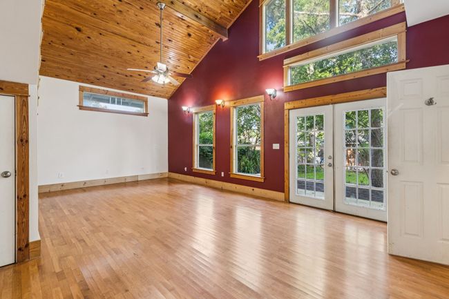 Unfurnished living room with high vaulted ceiling, wooden ceiling with exposed beams, wood finished floors, plenty of natural light, and a ceiling fan | Image 18
