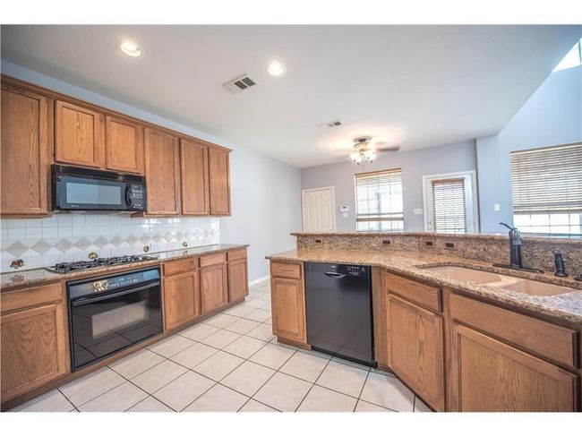 Kitchen with black appliances, a sink, brown cabinetry, tasteful backsplash, and recessed lighting | Image 5