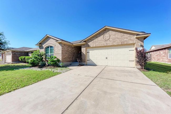 Single story home with brick siding, a garage, a front lawn, and driveway | Image 6