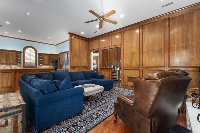 Living room with wood finished floors, a ceiling fan, crown molding, and recessed lighting | Image 11