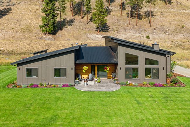 Rear view of property featuring a patio area, a yard, a chimney, and board and batten siding | Image 4