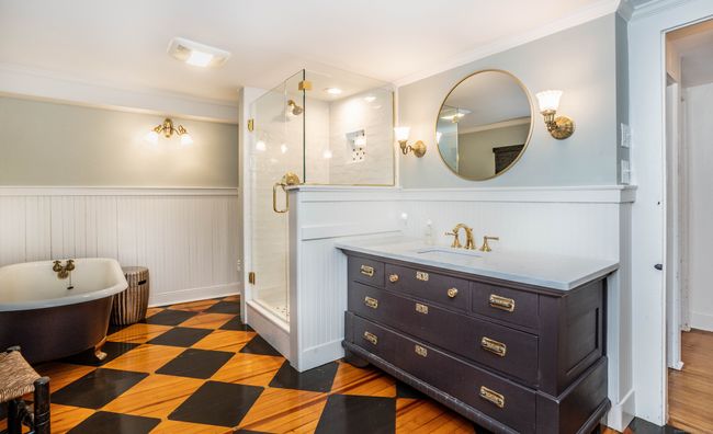 This modern bathroom keeps the charm but allows enjoyment with its clawfoot tub, tiled stall shower, and unique vanity. | Image 26