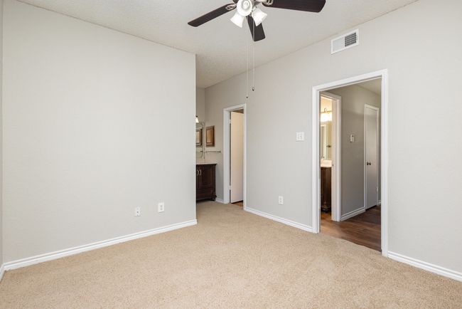 Unfurnished bedroom with carpet flooring, connected bathroom, a textured ceiling, and ceiling fan | Image 11