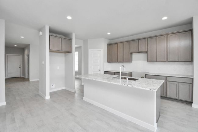 This kitchen is by far any chef’s dream! This spacious kitchen features high ceilings, stained wood cabinets, granite countertop, SS appliances, modern tile backsplash, recessed lighting, extended counter space, granite kitchen island with double sink, and space for breakfast bar, and a walk-in pantry all overlooking your huge family room. | Image 13