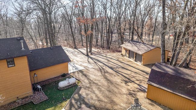 An aerial view from over the customized workshop garage. There is substantial parking with the 1-car garage, the 2-car garage, the workshop garage, the turnaround, & the driveway. All of this is surround by mature oak trees. | Image 5