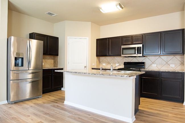 Kitchen with appliances with stainless steel finishes, backsplash, light wood finished floors, and a sink | Image 7
