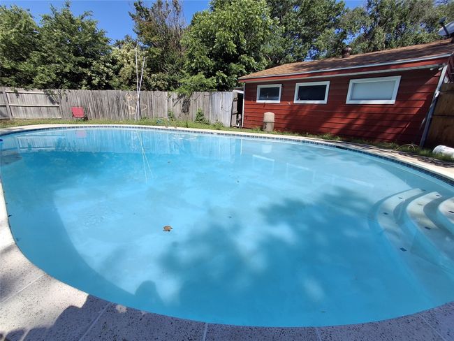 View of swimming pool featuring a fenced backyard and view of scattered trees | Image 26
