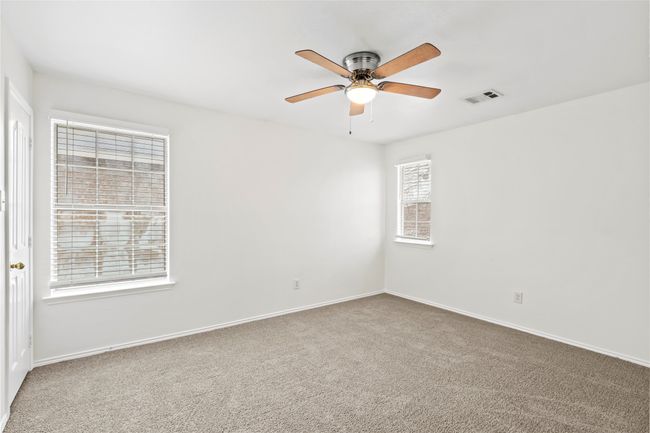 Empty room with visible vents, carpet floors, baseboards, and ceiling fan | Image 17