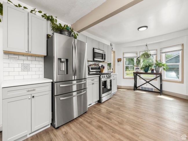 Kitchen with stainless steel appliances, light countertops, tasteful backsplash, light wood finished floors, and beam ceiling | Image 7