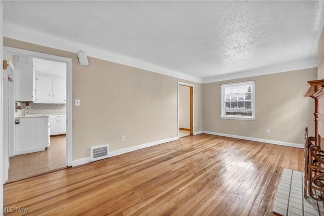 Unfurnished living room featuring light wood-style flooring, a textured ceiling, a sink, baseboards, and visible vents | Image 28