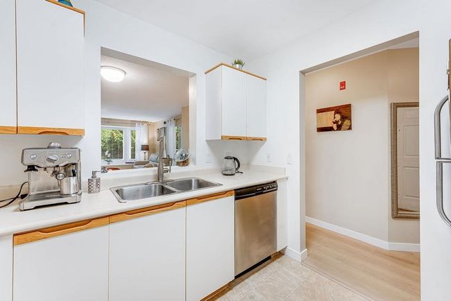 Kitchen with dishwasher, light countertops, a sink, white cabinetry, and baseboards | Image 7