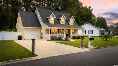 New england style home featuring a garage, a porch, and a yard | Image 1