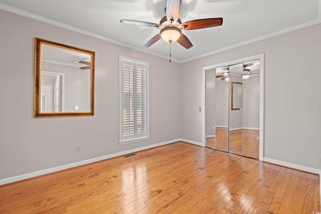 Unfurnished bedroom featuring wood-type flooring, ornamental molding, ceiling fan, and a closet | Image 13