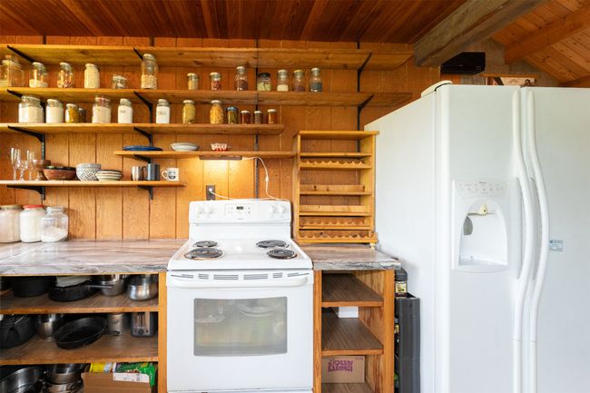 Kitchen with white appliances, open shelves, wood ceiling with exposed beams, and light countertops | Image 32
