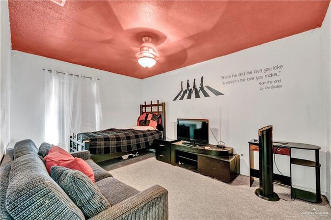 Carpeted bedroom with a textured ceiling, ceiling fan, and baseboards | Image 5