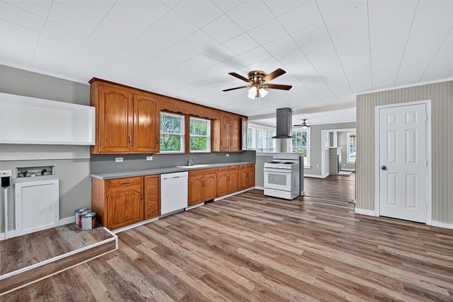 Kitchen featuring crown molding, brown cabinetry, white appliances, light wood-style floors, and island exhaust hood | Image 10