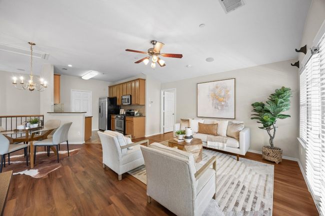 Living room featuring high ceiling fan, vinyl wood flooring, a chandelier, in the dining area | Image 9