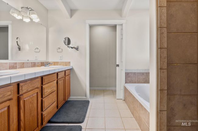 Full bath featuring double vanity, tile patterned floors, and a tiled shower & separate soaking tub | Image 25