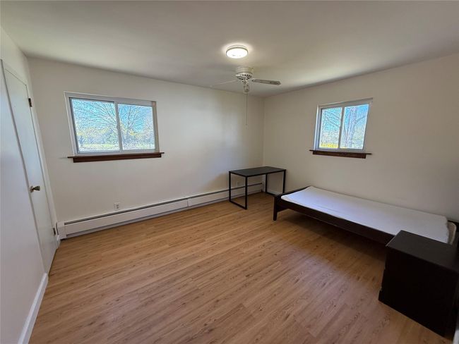 Unfurnished bedroom featuring baseboards, wood finished floors, and a baseboard radiator | Image 9