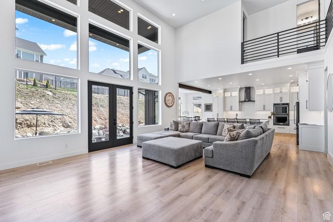 Living area featuring french doors, light wood-style flooring, a towering ceiling, and baseboards | Image 14