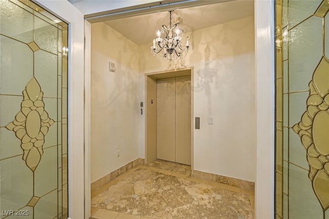 Entryway featuring elevator, light stone finish flooring, a chandelier, and baseboards | Image 4