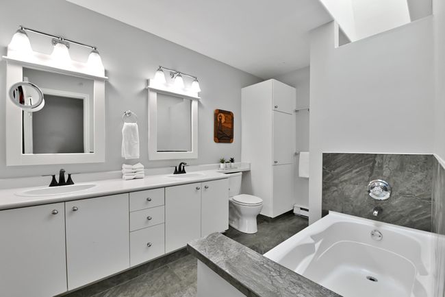 Bathroom featuring toilet, a bath, a baseboard heating unit, and a sink | Image 28