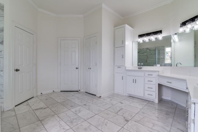 Bathroom featuring vanity, crown molding, walk in shower, marble look tile flooring, and baseboards | Image 15