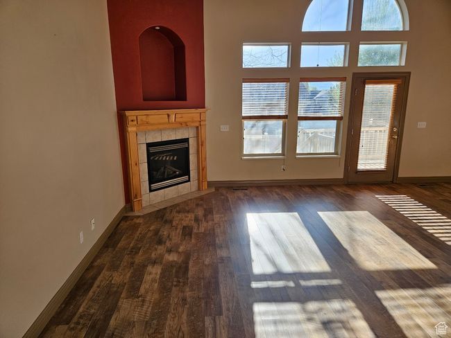 Unfurnished living room featuring baseboards, a tile fireplace, a healthy amount of sunlight, and dark wood-style floors | Image 5