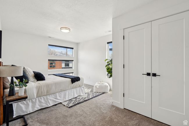 Carpeted bedroom with a closet, visible vents, a textured ceiling, and multiple windows | Image 28