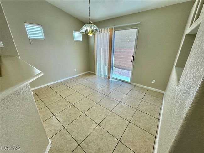 Unfurnished dining area featuring an inviting chandelier, light tile patterned flooring, and baseboards | Image 5