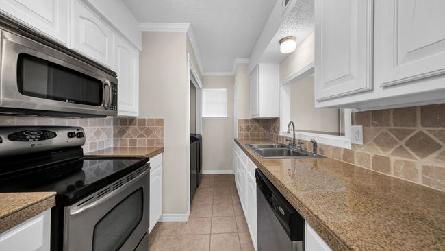 Kitchen featuring backsplash, white cabinetry, sink, crown molding, and stainless steel appliances | Image 10