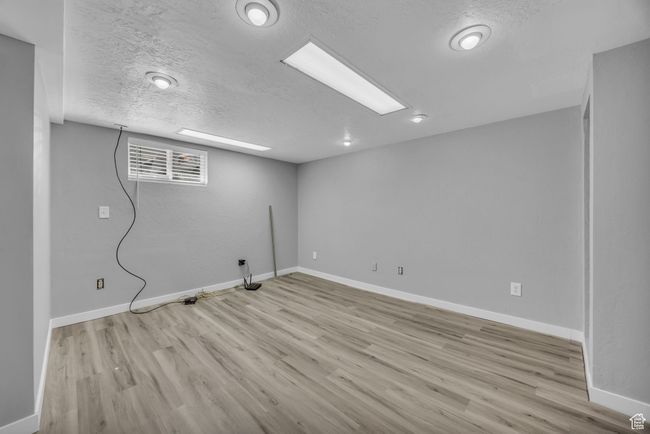 Basement featuring wood finished floors, baseboards, and a textured ceiling | Image 17