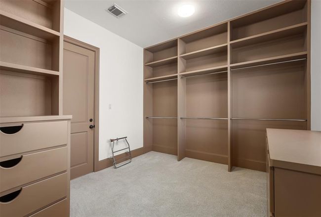 Spacious Primary walk-in closet with ample shelving and hanging space, featuring built-in drawers and a neutral color palette. Ideal for organized storage. | Image 37